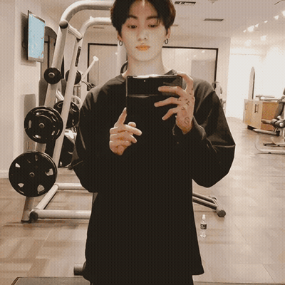 A Man Is Taking A Picture Of Himself In A Gym With His Phone GIF
