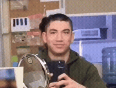 A Man Is Taking A Picture Of Himself In A Mirror . GIF