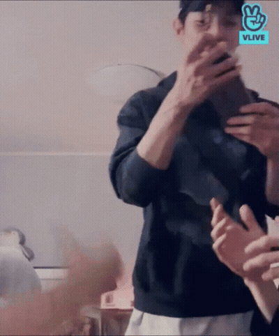 A Man Is Taking A Picture Of Himself In A Mirror With A Vlive Logo Behind Him GIF