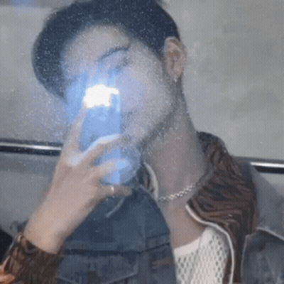 A Man Is Taking A Picture Of Himself In A Mirror With His Phone . GIF
