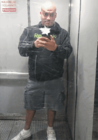 A Man Is Taking A Picture Of Himself In An Elevator With A Sign That Says Maximum Occupancy 7 Passengers GIF