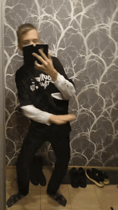 A Man Is Taking A Picture Of Himself In Front Of A Wall With A Pattern GIF