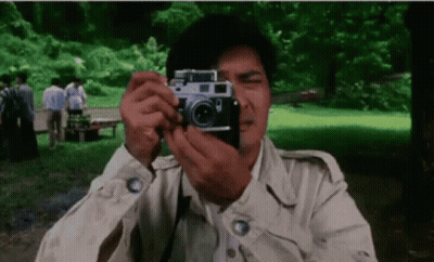 A Man Is Taking A Picture With A Camera In The Park . GIF
