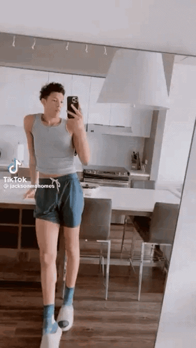 A Man Is Taking A Selfie In A Kitchen In Front Of A Mirror . GIF