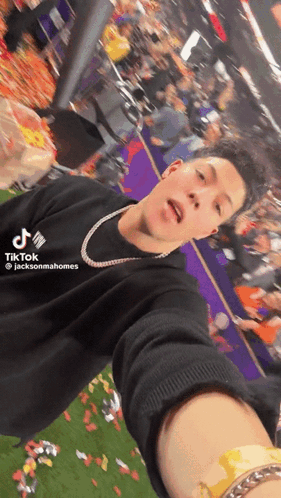 A Man Is Taking A Selfie In Front Of A Crowd While Wearing A Black Shirt That Says Tiktok GIF