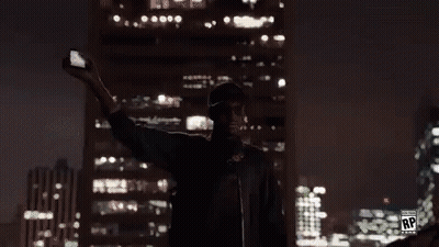 A Man Is Taking A Selfie In Front Of A Large Screen With The Letters Rp On It GIF