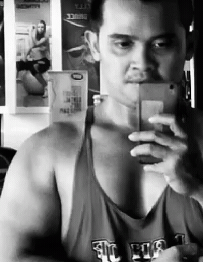 A Man Is Taking A Selfie In Front Of A Mirror . GIF