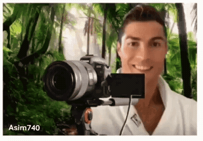A Man Is Taking A Selfie With A Camera In Front Of A Jungle Background . GIF
