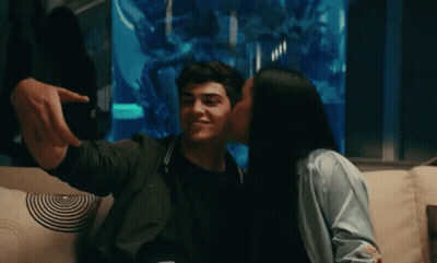 A Man Is Taking A Selfie With A Woman Who Is Kissing Him On The Cheek GIF
