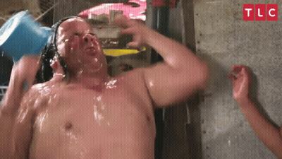 A Man Is Taking A Shower With A Bucket Of Water On His Head .. GIF