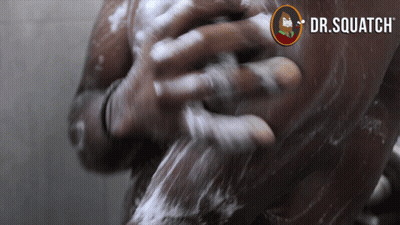A Man Is Taking A Shower With A Dr. Squatch Logo In The Background GIF