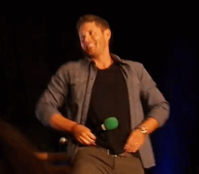 A Man Is Taking Off His Shirt On A Stage And Dancing . GIF