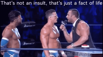 A Man Is Talking Into A Microphone In A Wrestling Ring While Two Other Men Look On . GIF