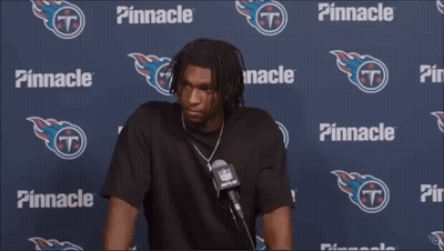 A Man Is Talking Into A Microphone In Front Of A Pinnacle Banner GIF