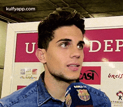 A Man Is Talking Into A Microphone In Front Of A Sign That Says Under GIF