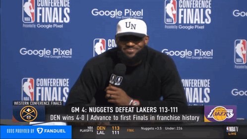 A Man Is Talking Into A Microphone In Front Of A Wall That Says Conference Finals On It GIF