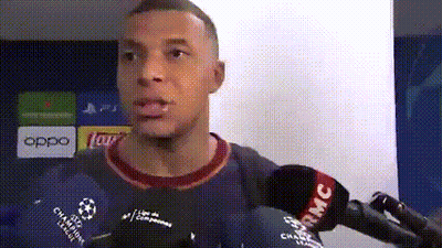 A Man Is Talking Into A Microphone While Wearing A Blue Shirt With A Soccer Ball On It . GIF