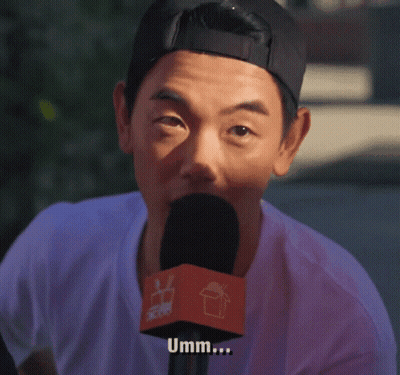 A Man Is Talking Into A Microphone With The Word Umm Written On It GIF
