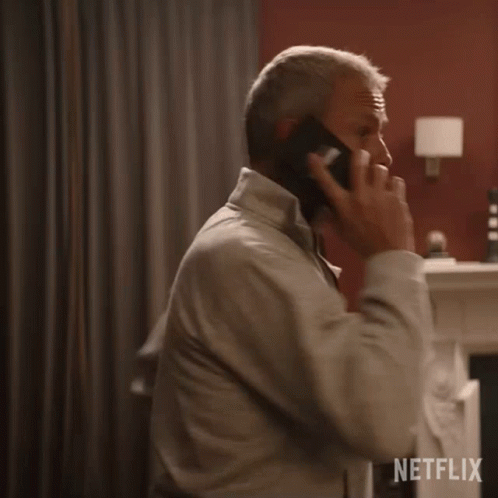 A Man Is Talking On A Cell Phone In A Room With A Netflix Logo In The Corner GIF
