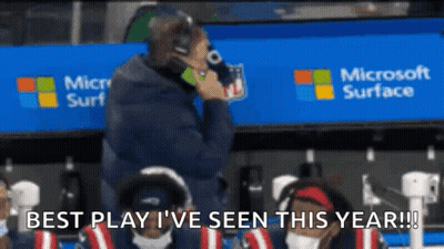A Man Is Talking On A Cell Phone In Front Of A Microsoft Surface Sign GIF