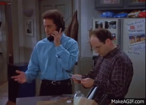 A Man Is Talking On A Cell Phone While Another Man Looks At A Book . GIF