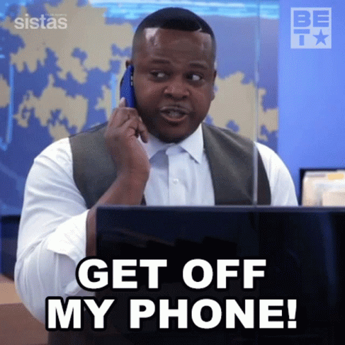 A Man Is Talking On A Cell Phone While Sitting In Front Of A Laptop . GIF