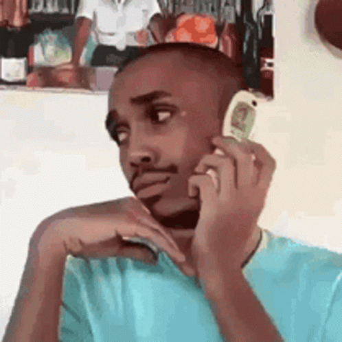 A Man Is Talking On A Cell Phone While Sitting In Front Of A Picture . GIF