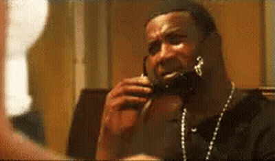 A Man Is Talking On A Cell Phone While Wearing A Necklace . GIF