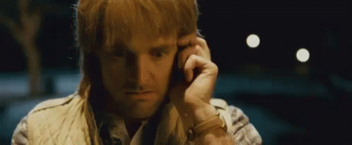 A Man Is Talking On A Cell Phone While Wearing A Vest . GIF
