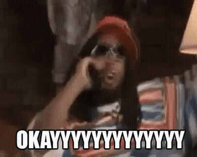 A Man Is Talking On A Cell Phone While Wearing Sunglasses And A Hat . GIF
