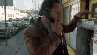 A Man Is Talking On A Pay Phone With A Sign That Says ' Pay Here And Get Paid ' On It GIF