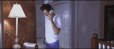 A Man Is Talking On A Phone In A Dark Room GIF