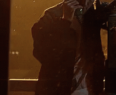 A Man Is Talking On A Phone In Front Of A Window With Rain Drops On It GIF