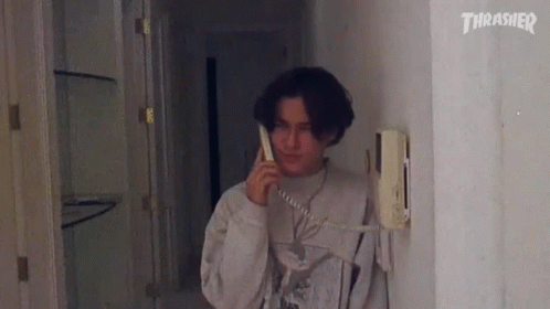 A Man Is Talking On A Telephone In A Hallway . GIF