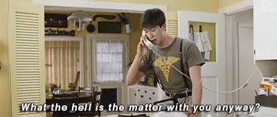 A Man Is Talking On A Telephone In A Kitchen . GIF