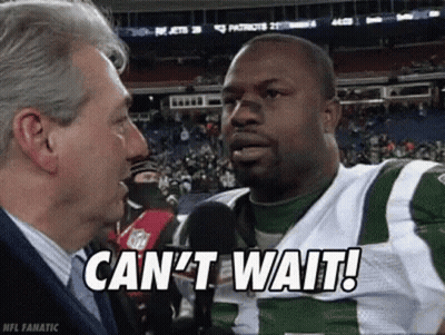 A Man Is Talking To A Football Player Who Is Wearing A Green And White Uniform . GIF