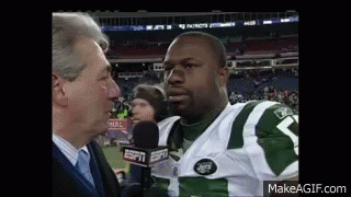A Man Is Talking To A Football Player Who Is Wearing A Jets Uniform . GIF