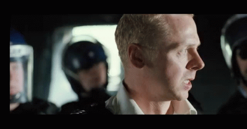 A Man Is Talking To A Group Of Police Officers In Riot Gear . GIF