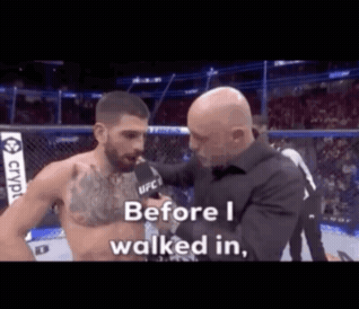 A Man Is Talking To Another Man In A Boxing Ring While A Referee Looks On . GIF