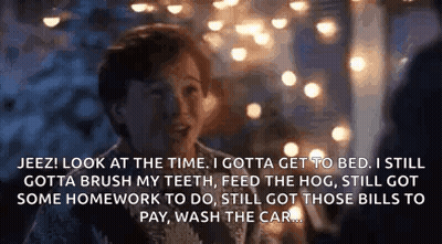 A Man Is Talking To Another Man In Front Of A Christmas Tree While Sitting At A Table . GIF