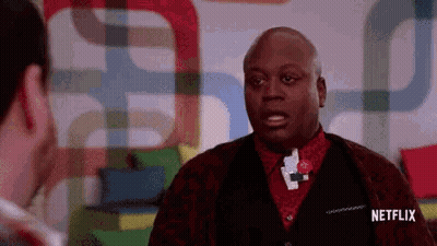 A Man Is Talking To Another Man In Front Of A Colorful Wall . GIF