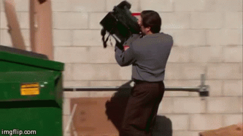 A Man Is Throwing A Backpack Into A Dumpster .. GIF