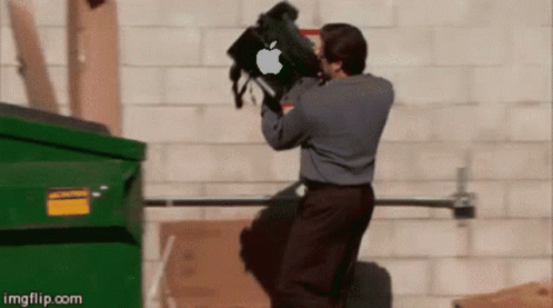 A Man Is Throwing A Bag With An Apple Logo On It Into A Dumpster GIF