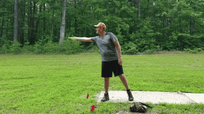 A Man Is Throwing A Frisbee In A Grassy Field GIF