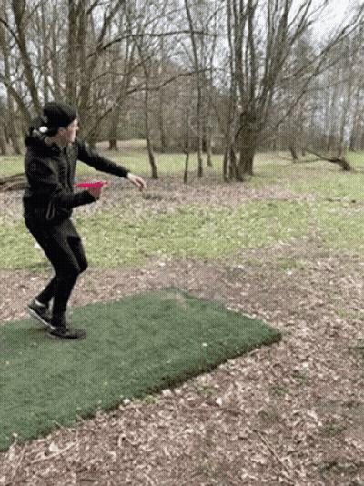 A Man Is Throwing A Frisbee On A Frisbee Course In The Woods . GIF