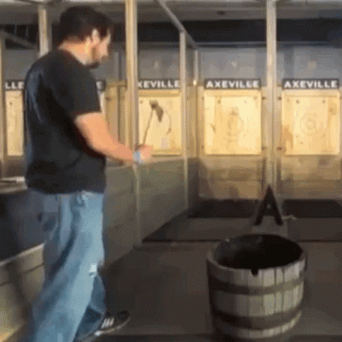 A Man Is Throwing An Axe At A Target In A Axeville GIF