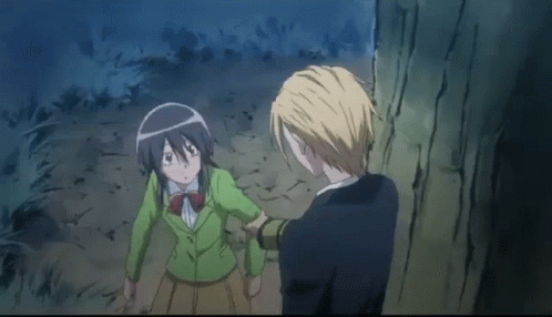 A Man Is Touching A Girl 'S Face While They Are Standing Next To Each Other In A Forest . GIF