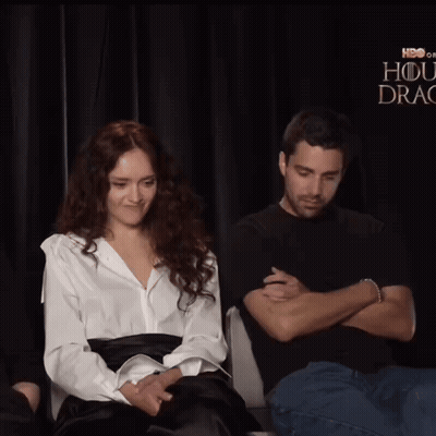 A Man Is Touching A Woman 'S Ear In Front Of A Sign That Says Hbo GIF
