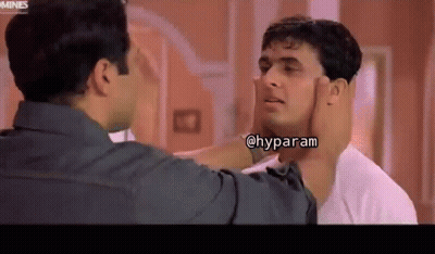 A Man Is Touching Another Man 'S Face In A Room . GIF