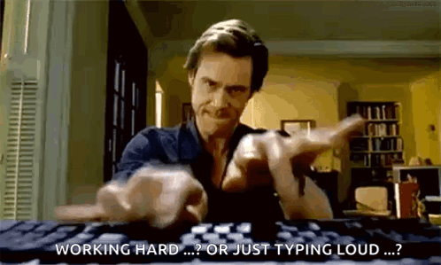 A Man Is Typing On A Computer Keyboard And Pointing At The Camera . GIF